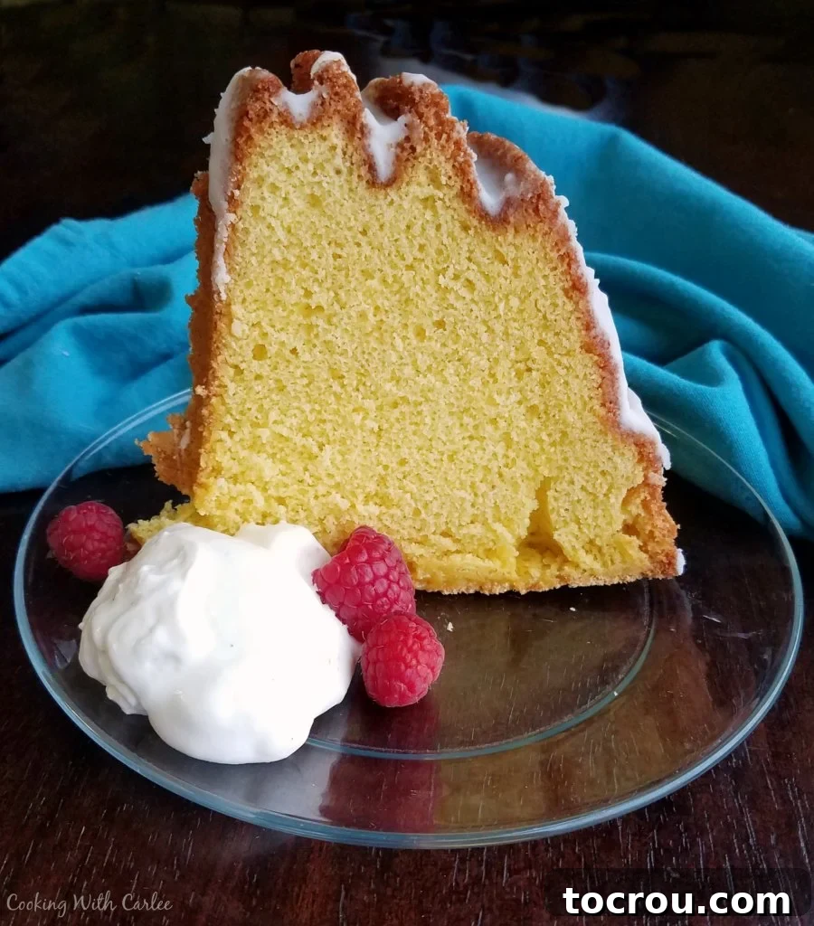 Delicious Egg Yolk Gold Cake Slice A delectable slice of Vintage Gold Cake standing on a glass plate, accompanied by a generous dollop of whipped cream and a scattering of fresh berries.