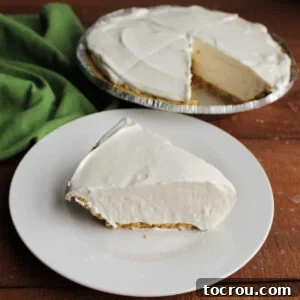 Frozen Key Lime Pie Slice of creamy frozen key lime pie with fluffy filling in graham cracker crust on plate with remaining pie in background.