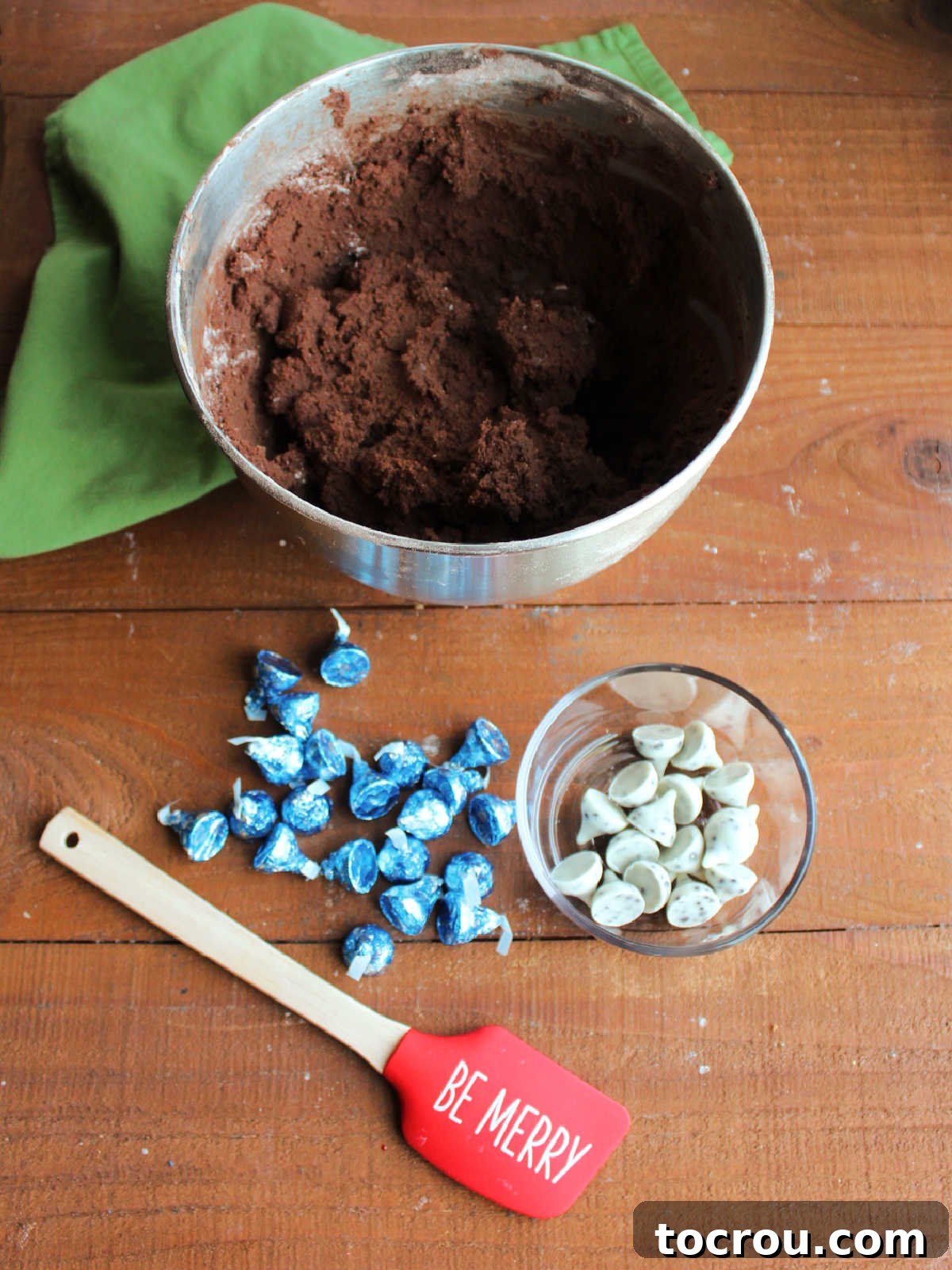 Oreo Dream Blossoms 4 A bowl filled with rich, thick chocolate cookie dough, prepared and ready to be shaped. Next to it, a generous pile of Hershey's Kisses awaits, poised to transform the simple cookie dough into delightful blossom cookies.