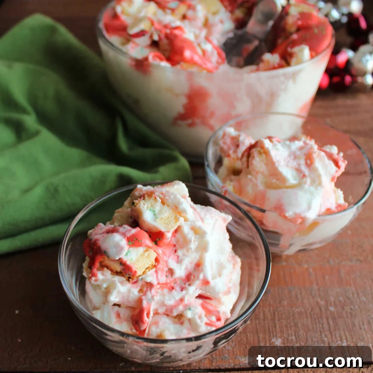 Scoops of creamy vanilla ice cream with visible bits of Christmas tree snack cakes and a swirl of red marshmallow fluff frosting, presented in a bowl and ready to be enjoyed as a festive dessert.