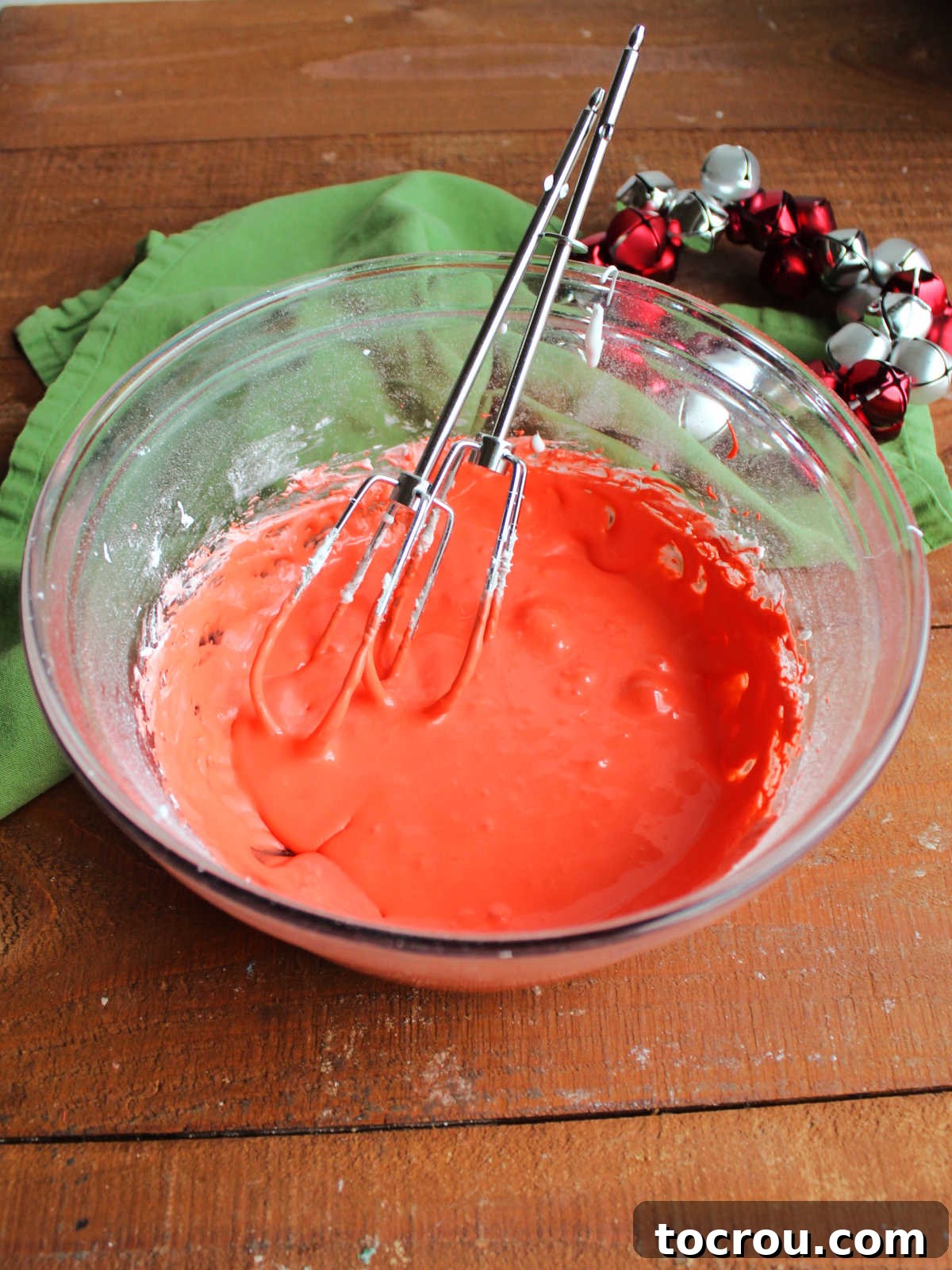 A vibrant red marshmallow fluff frosting, whipped to a smooth consistency and presented in a mixing bowl, ready to be piped and layered into the Christmas tree cake ice cream.