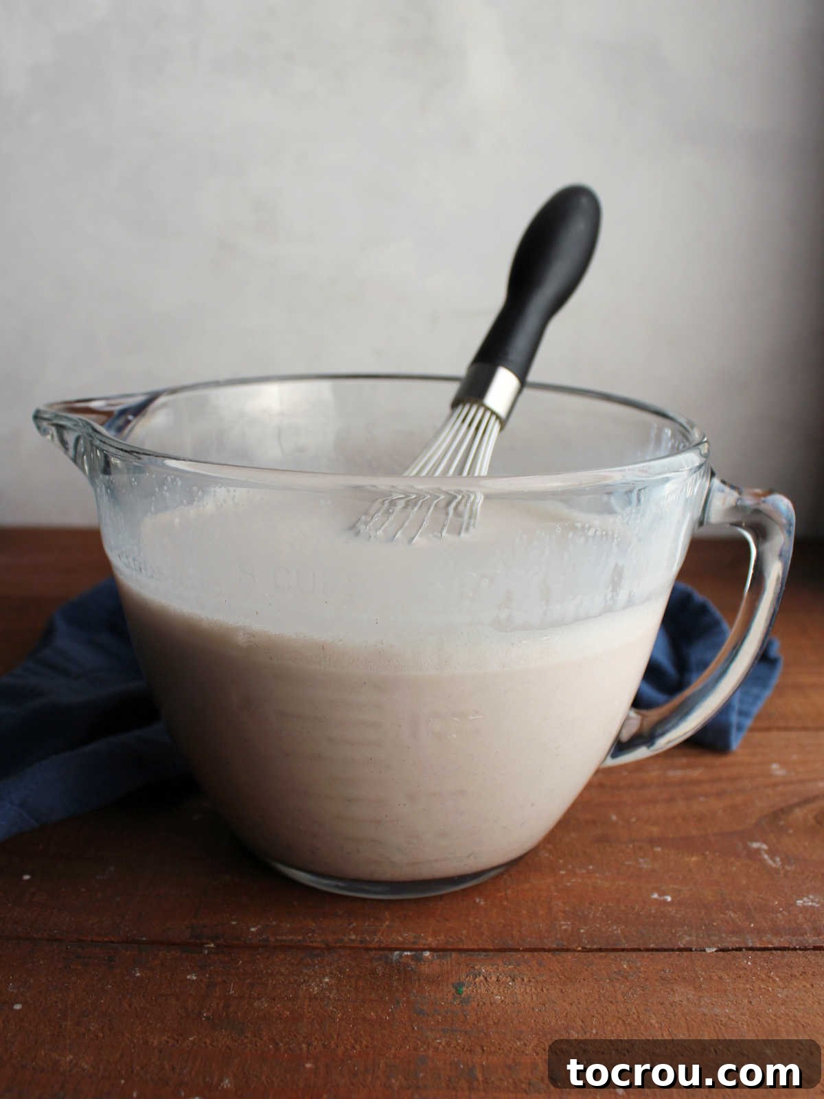 Glass batter bowl filled with apple butter ice cream base and a balloon whisk, ready to be churned.