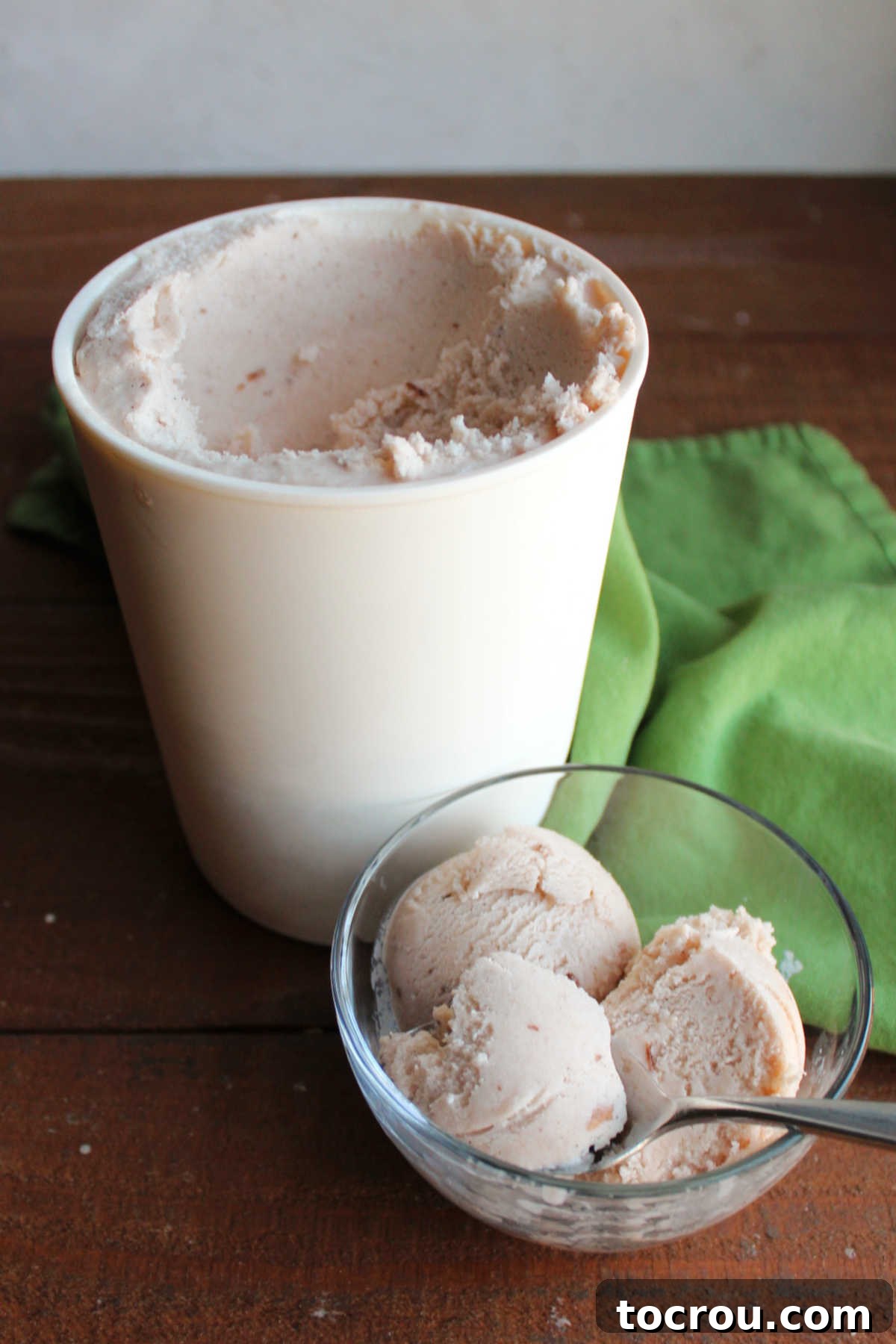 Spoon getting a bite of homemade apple butter ice cream showing creamy texture and light tan color.