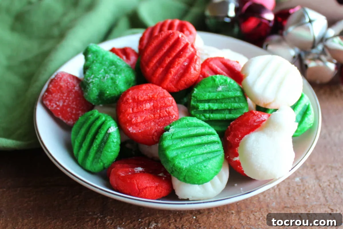 Creamy Dream Mints 2 Close up of a bowl with Christmas colored cream cheese mints, some round with fork marks, plus one shaped like a snowman and one like a Christmas tree.