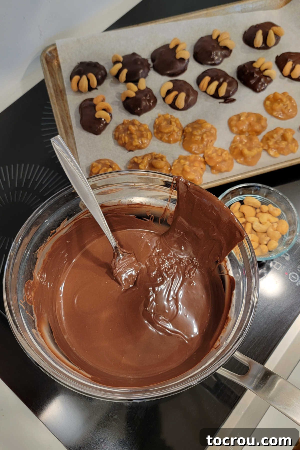 The process of dipping frozen caramel and cashew mounds into a bowl of melted hot chocolate, followed by decorating with additional cashews to achieve the distinct bear claw shape.