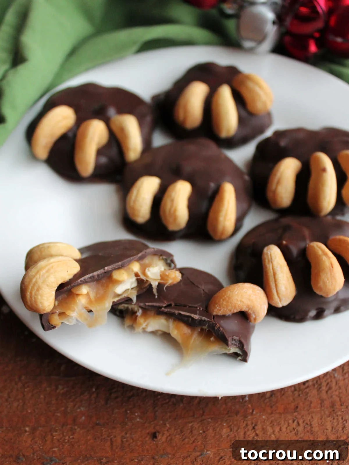 A beautifully arranged plate featuring several homemade bear paw candies, with one candy thoughtfully split open to reveal its enticing, chewy caramel and cashew interior, showcasing its perfect texture.