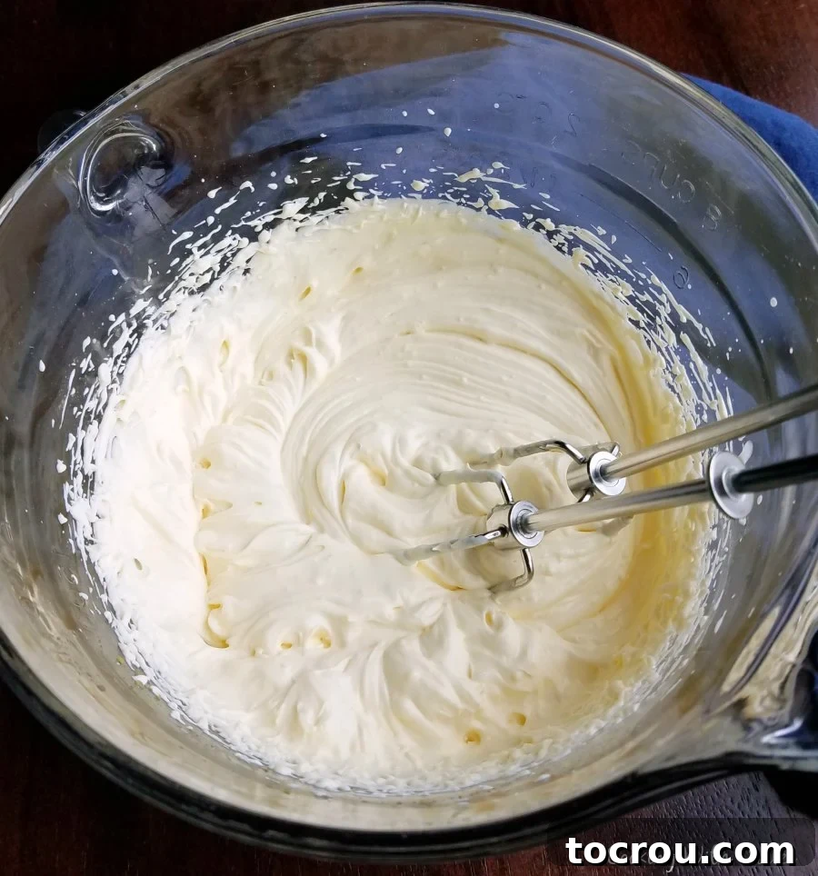 Sunshine Creamsicle Swirl 2 Mixing bowl with creamy vanilla pudding and whipped cream topping, beaters inside.
