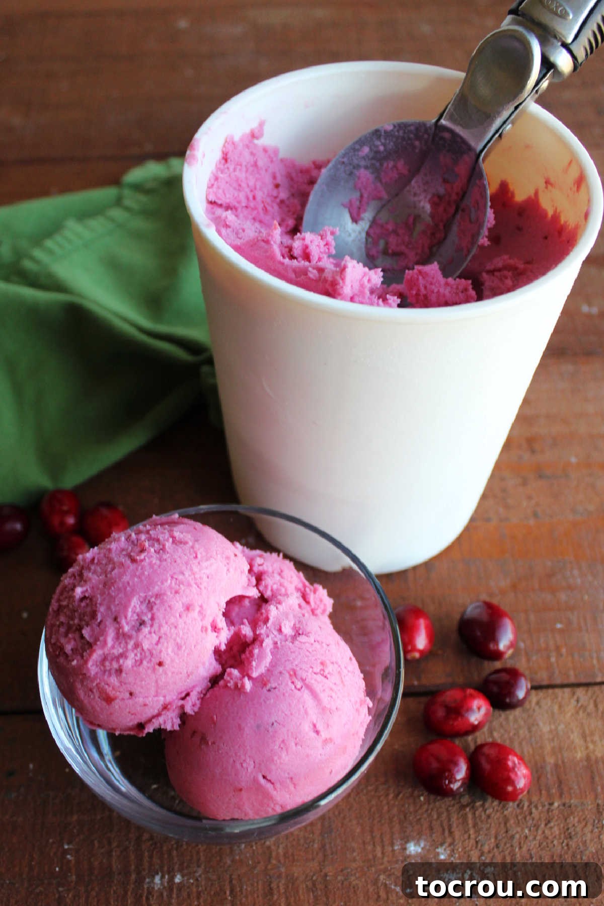 Crimson Cranberry Chill 7 Scoops of cranberry ice cream in small glass bowl next to storage container with more ice cream.