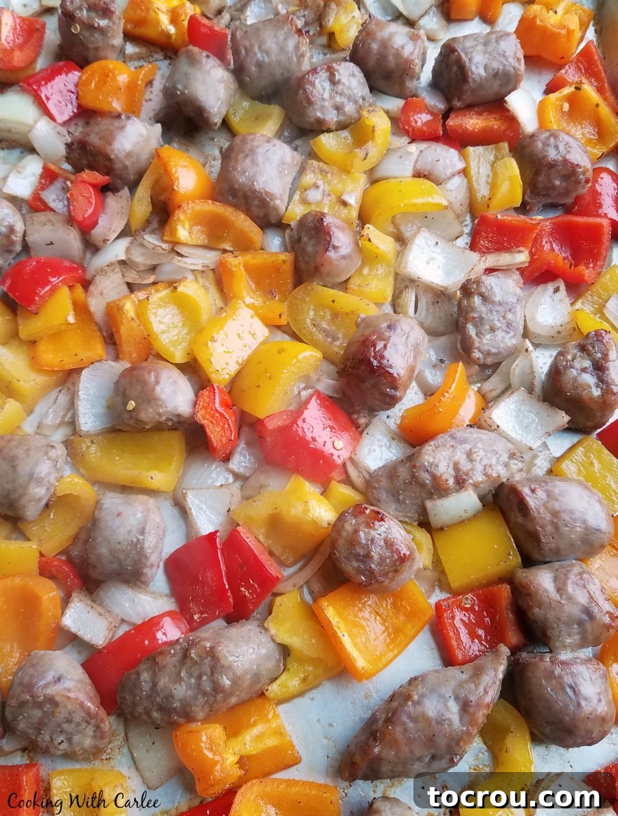 Roasted Italian sausage with a medley of colorful peppers and onions on a sheet pan, cooked to perfection. A sheet pan generously loaded with beautifully roasted Italian sausage, colorful bell peppers, and sweet onions, glistening and ready to serve.