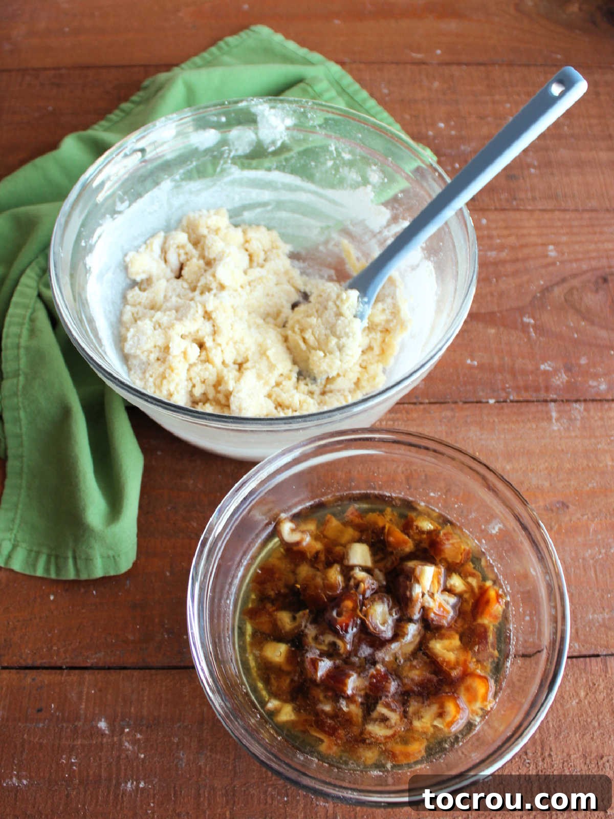 Mixing bowl with butter, sugar and flour mixture next to smaller bowl with chopped dates soaking in boiling water and baking soda mixture. 