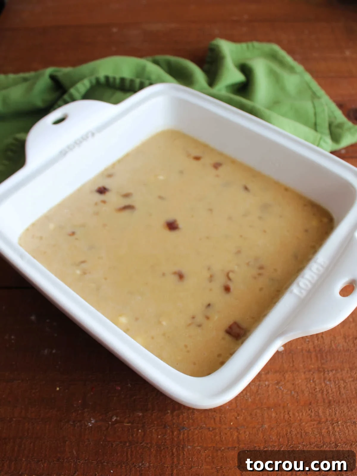 Date pudding batter in square baking dish, ready to go in the oven. 