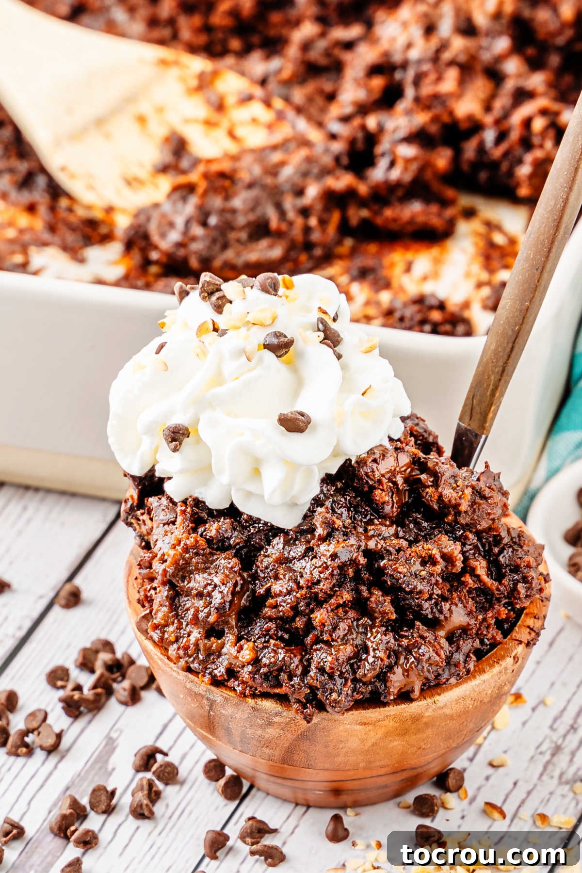 Effortless Chocolate Indulgence 7 Small bowl of gooey chocolate dump cake served with whipped cream and a spoon, ready to eat.