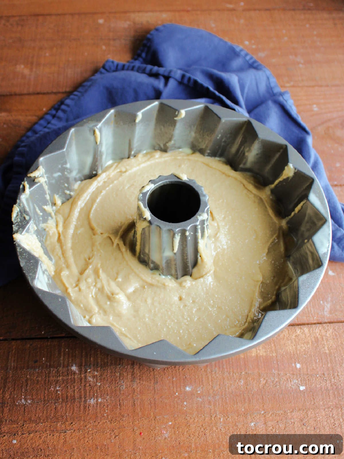 Bundt Cake Batter Tan-colored brown sugar pound cake batter evenly distributed in a Bundt cake tin, perfectly prepared and ready for baking.