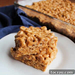 Two squares of delicious no-bake peanut butter Cheerio bars stacked, showing their dense, chewy texture and the rich peanut butter coating.