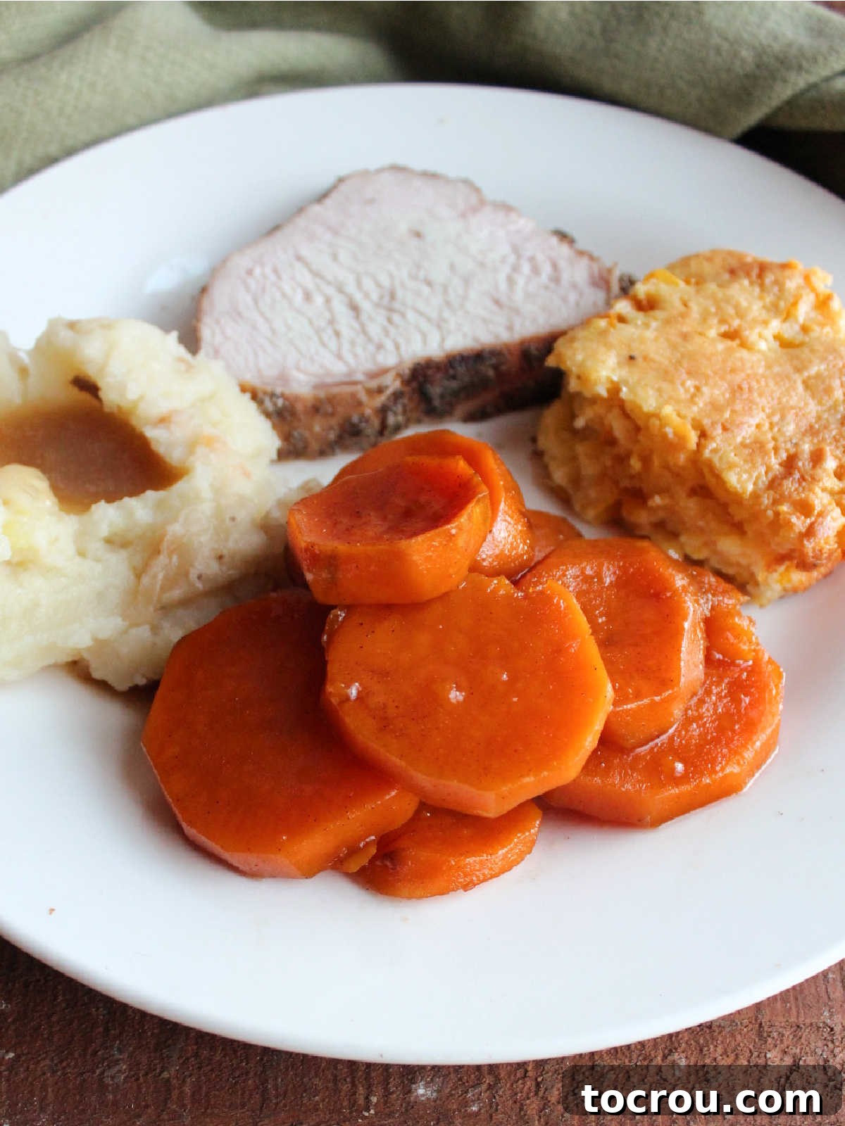 Candied sweet potatoes on plate with turkey and other side dishes, ready to eat. 