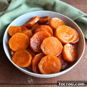 Bowl of sweet potatoes slices in brown sugar sauce after they have cooked in a slow cooker, ready to be served.