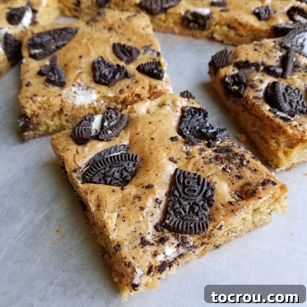Delicious brown sugar Oreo blondies with visible cookie pieces on top, arranged for serving on a white plate.