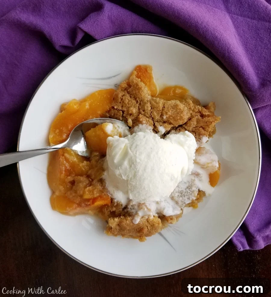Brown Sugar Peach Cobbler with Ice Cream Serving of peach cobbler with warm peach slices and brown sugar biscuit like topping served with a scoop of vanilla ice cream.