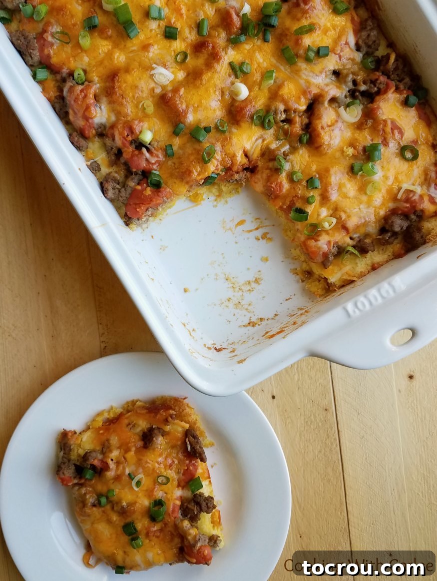 A Hearty and Delicious Turkey Tamale Casserole Ready to Serve A close-up view of a freshly baked turkey tamale casserole, revealing the bubbling melted cheese, rich red enchilada sauce, and the soft corn base, with a serving spoon poised to dish out a portion.