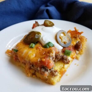 square of tamale casserole topped with sour cream, jalapenos and chives.