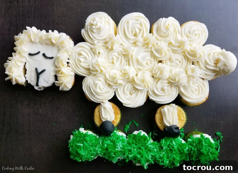 Sheep shaped cupcake pull apart cake ready for a spring or Easter celebration, decorated with fluffy white frosting and green coconut grass.