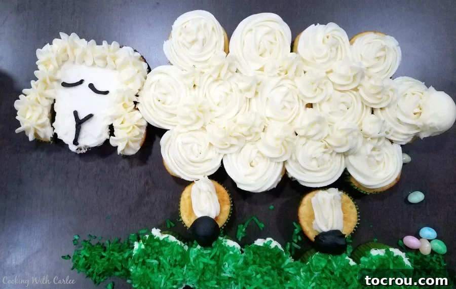 Finished sheep cupcake pull-apart cake with humorous jelly bean 'poops' scattered on the green grass, ready for a fun celebration.