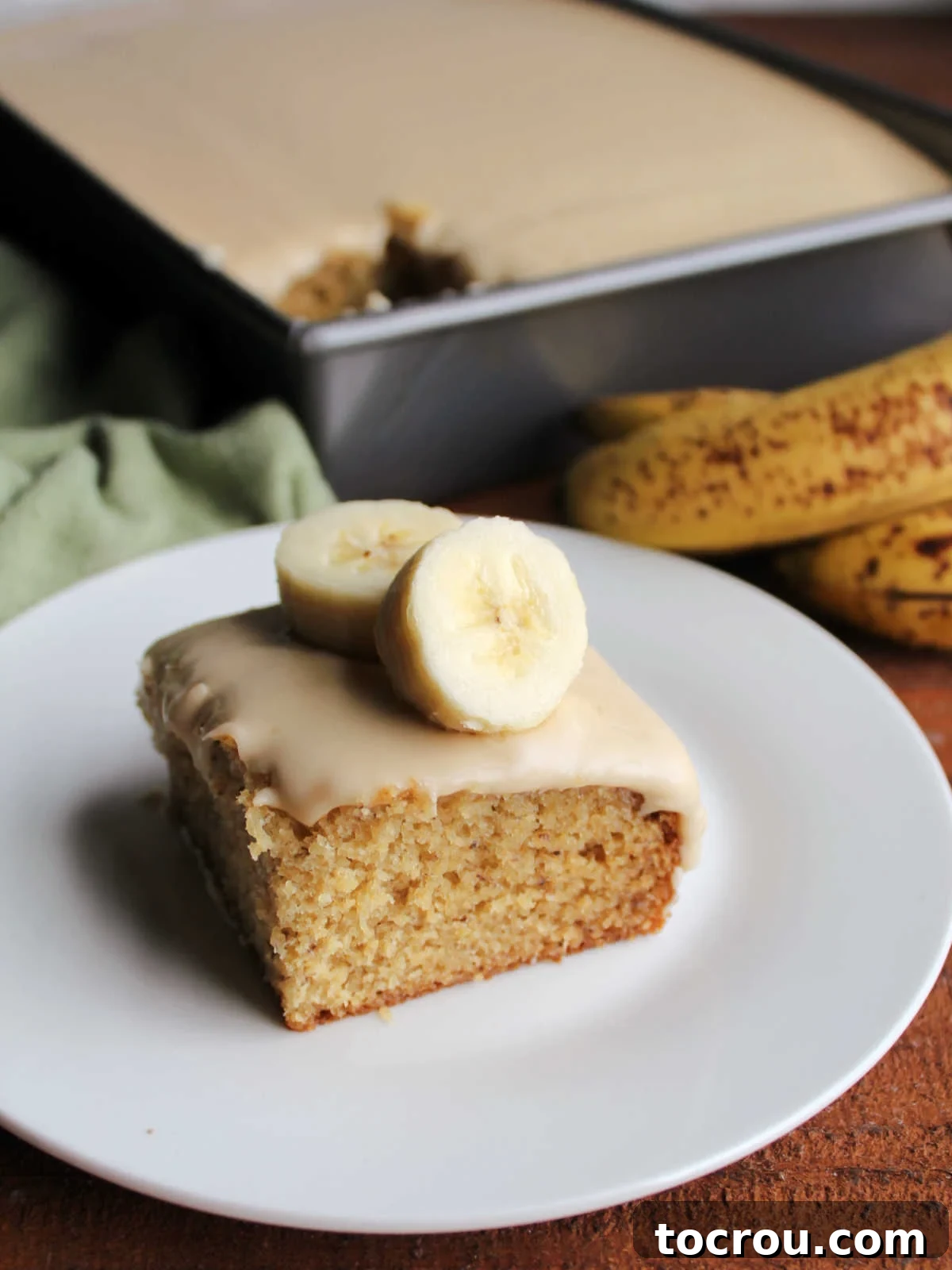 Golden Banana Cake Crowned with Brown Sugar Glaze 11 Banana cake with brown sugar icing topped with fresh banana slices.