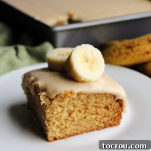 Golden Banana Cake Crowned with Brown Sugar Glaze 12 Square piece of banana cake topped with brown sugar icing and a couple of banana slices, ready to eat.
