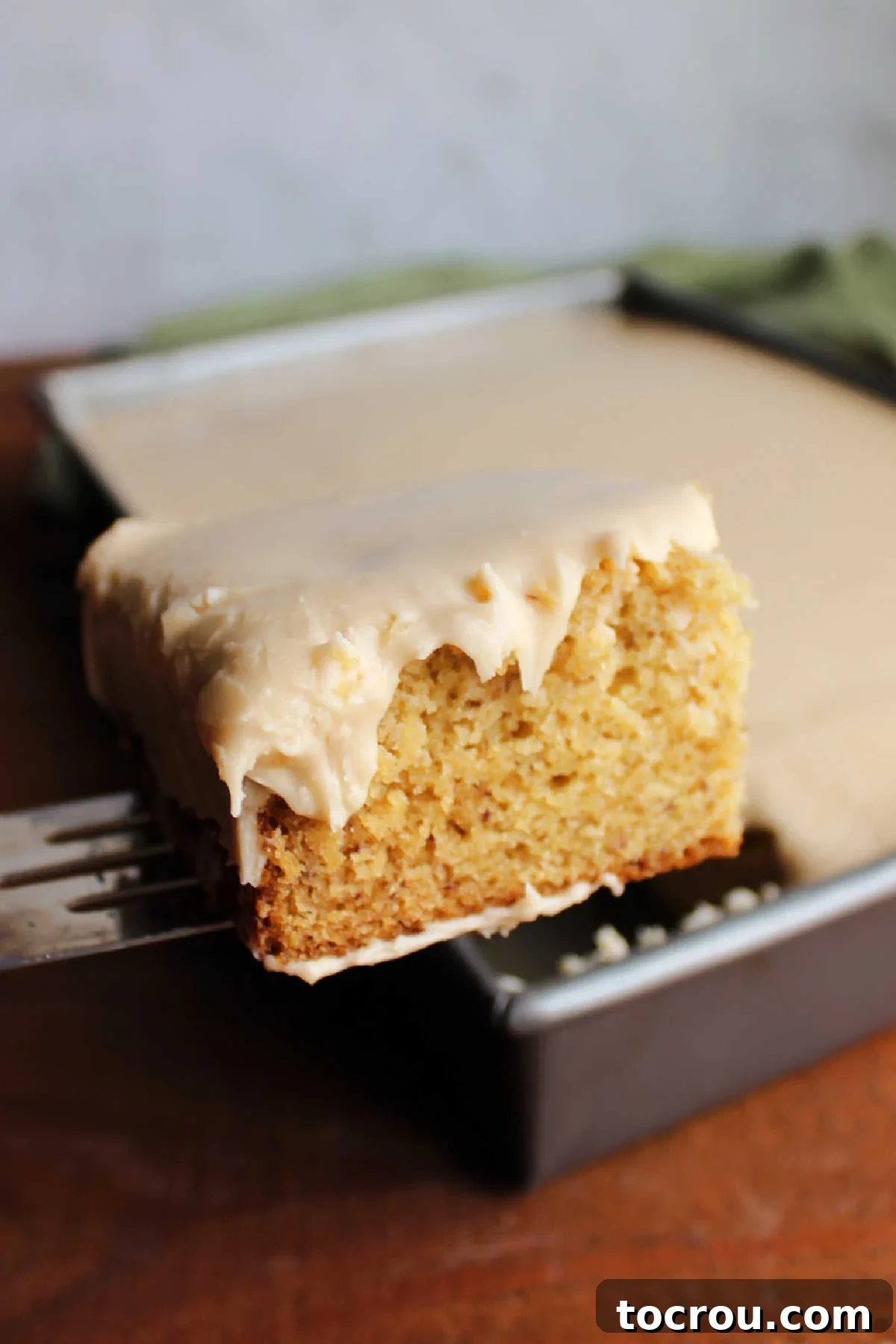 Golden Banana Cake Crowned with Brown Sugar Glaze 10 Lifting out first slice of brown sugar frosting topped banana cake out of the pan.