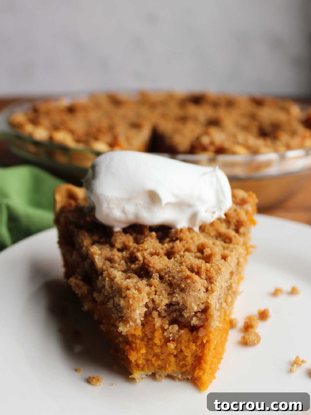 Spiced Carrot Pie with Crunchy Cinnamon Streusel 13 Slice of carrot pie topped with whipped cream, one bite missing from the top of the slice showing filling.
