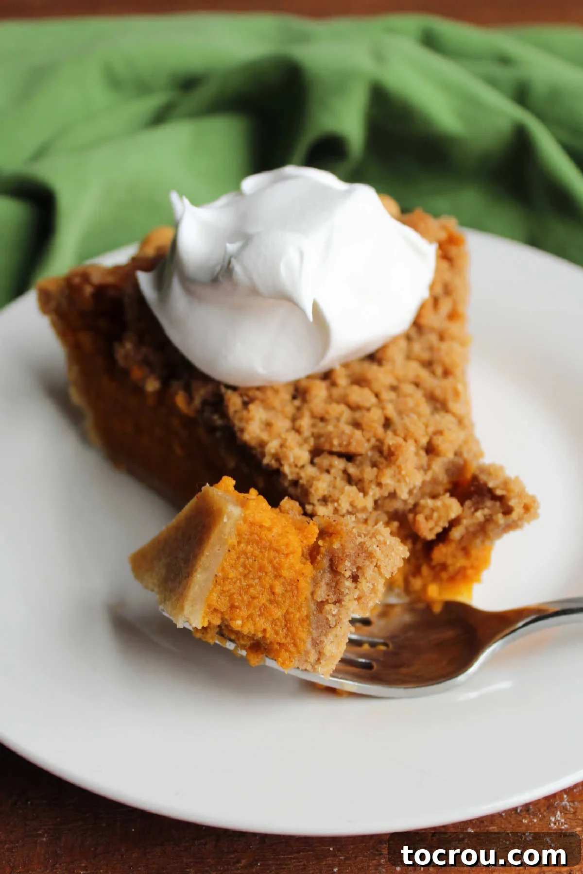 Spiced Carrot Pie with Crunchy Cinnamon Streusel 3 Bite of carrot crumb pie on fork next to slice of pie topped with fluffy white whipped cream on top.