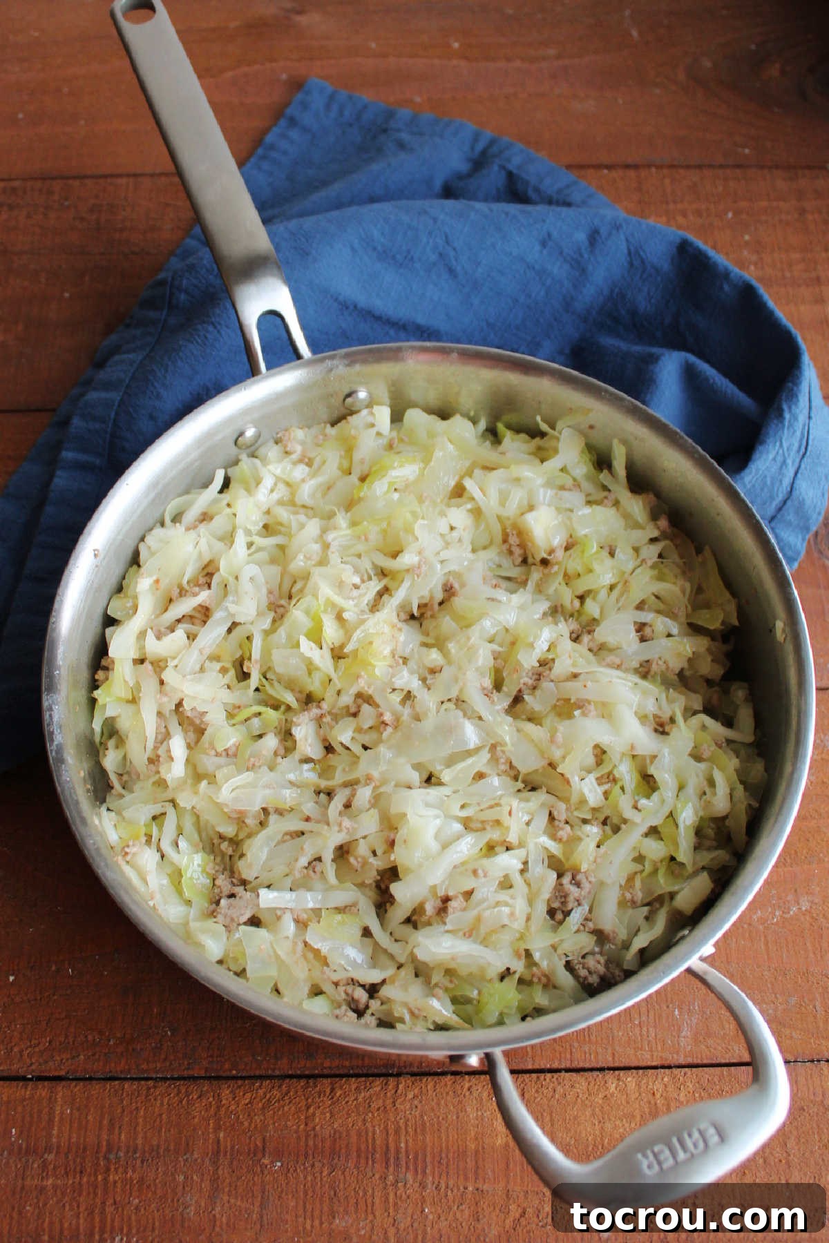 Succulent browned ground pork simmering in a skillet alongside softened, wilted cabbage and translucent onions, forming the flavorful base of the chow mein.