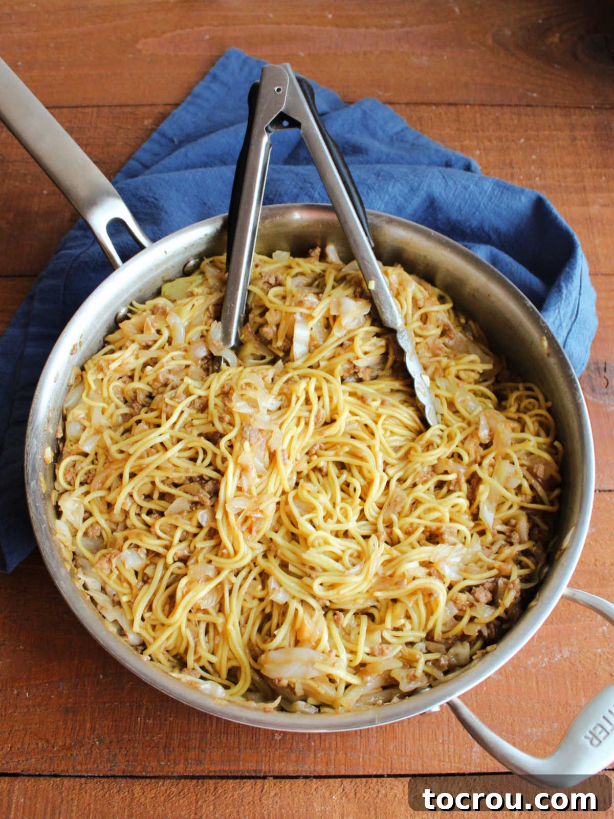 The finished pork chow mein, showcasing perfectly coated noodles, ground pork, and vegetables glistening with sauce in a large skillet, ready for serving.