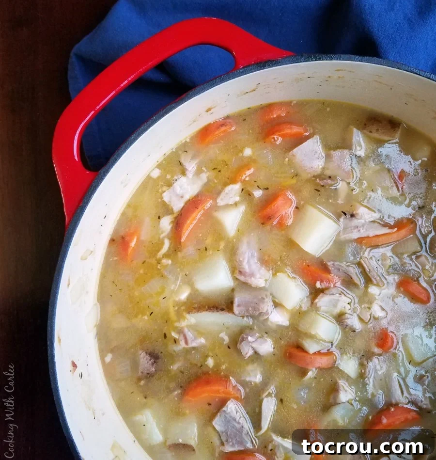 Red dutch oven filled with shortcut chicken stew with potatoes and carrots, perfectly cooked.