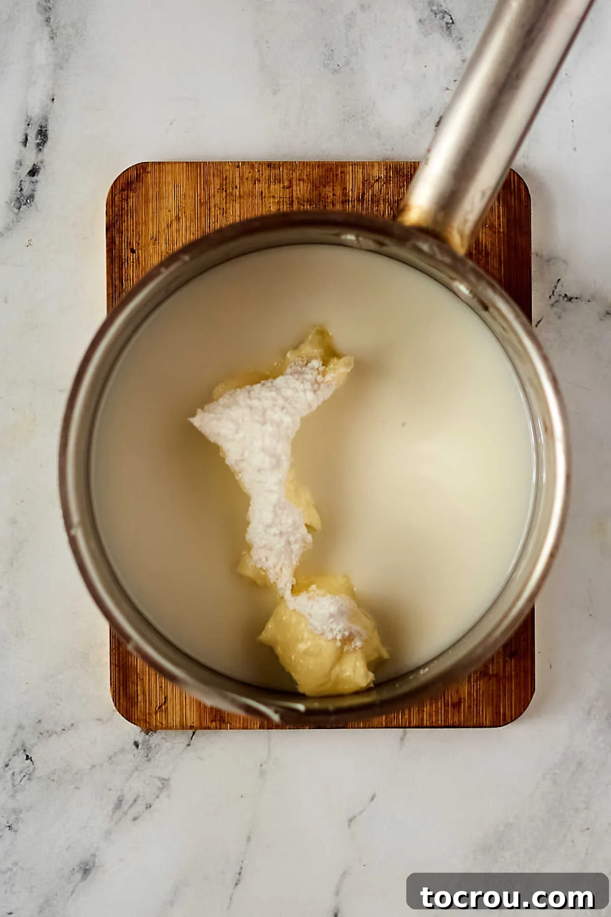 Melting butter and milk for the base of the lemon icing. Melting together butter, milk, and powdered sugar for icing.