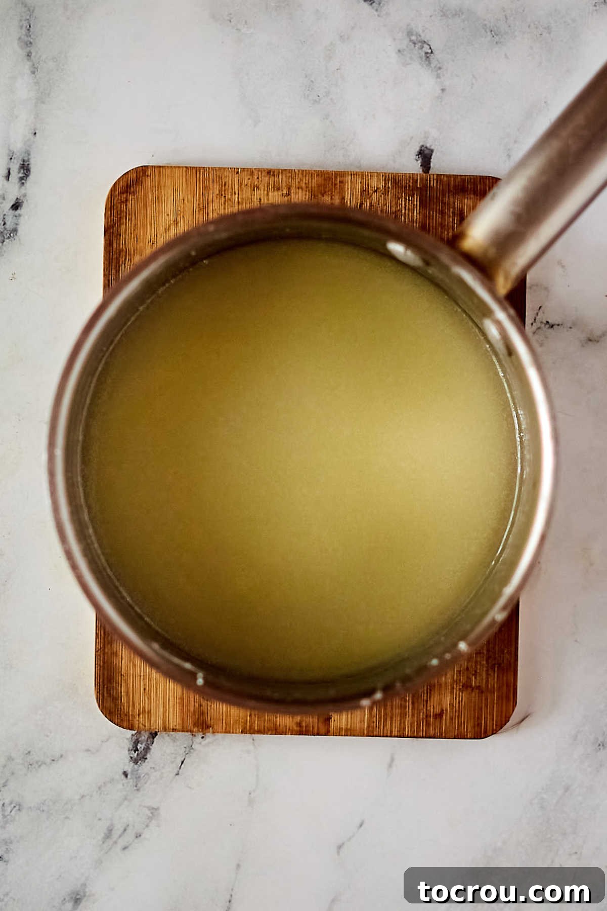 Warm lemon icing, perfectly smooth and ready to adorn the cake. Hot lemon icing mixture in saucepan ready to be poured over baked cake.