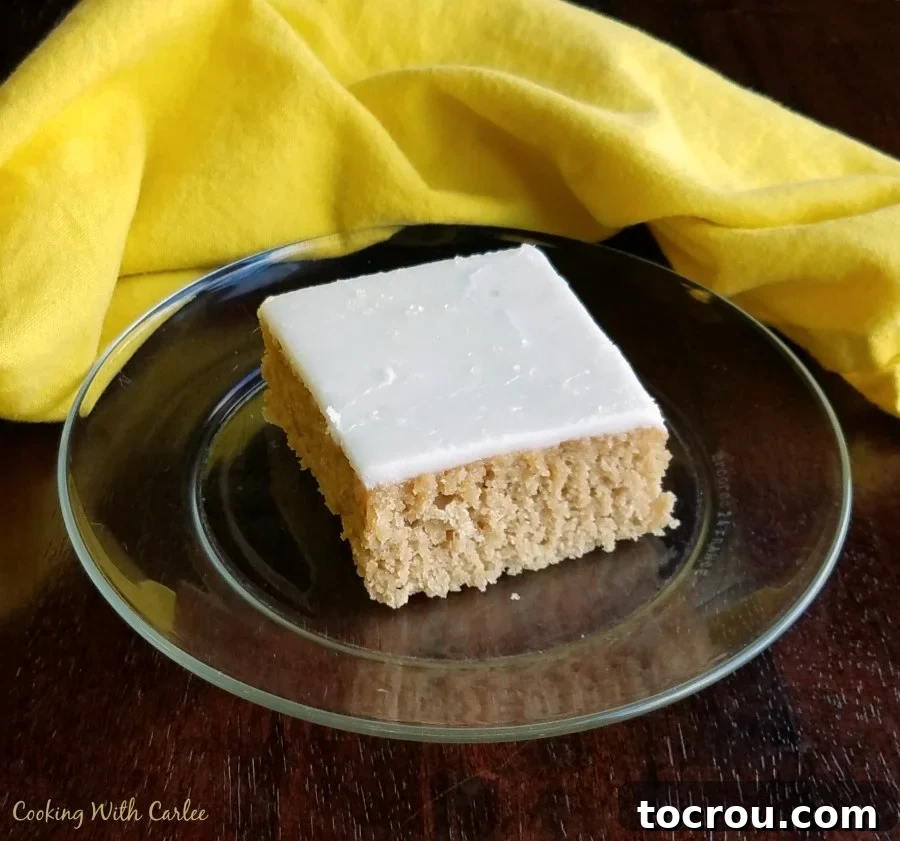 A perfect slice of Arnold Palmer Texas Sheet Cake, ready to be savored. piece of Arnold Palmer cake with tea flavored cake layer and smooth lemon icing on glass plate ready to eat.