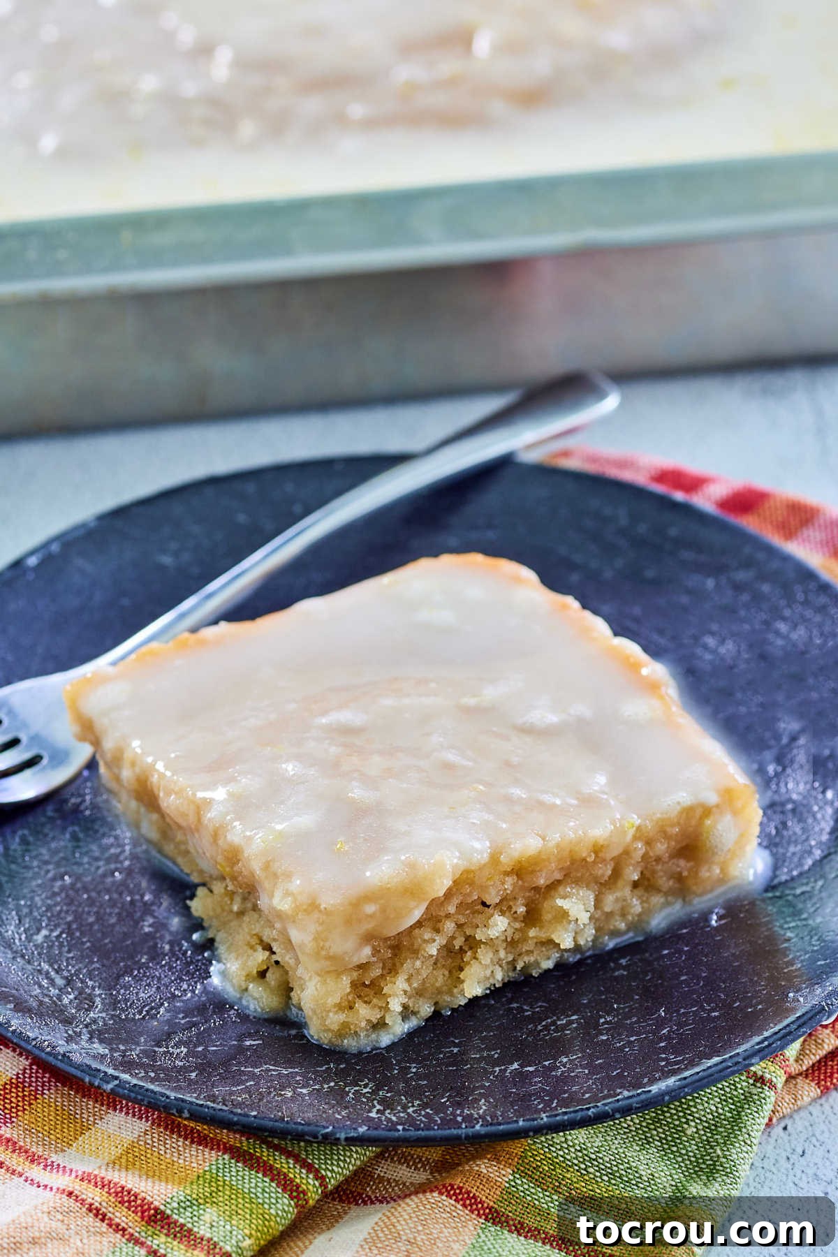 A delightful slice of tea-flavored sheet cake with smooth lemon icing. Piece of tea flavored sheet cake with lemon icing, ready to eat.