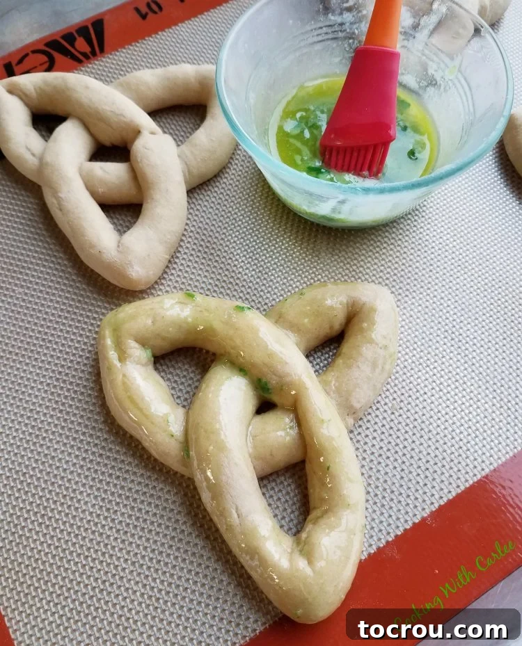 Brush a baked Celtic knot roll with vibrant herb butter, ready to enhance its flavor and appearance.