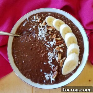bowl of chocolate oatmeal topped with sliced bananas, coconut and pecans.