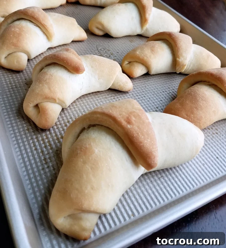 A baking sheet filled with golden baked crescent rolls, glistening and fresh from the oven, radiating warmth.