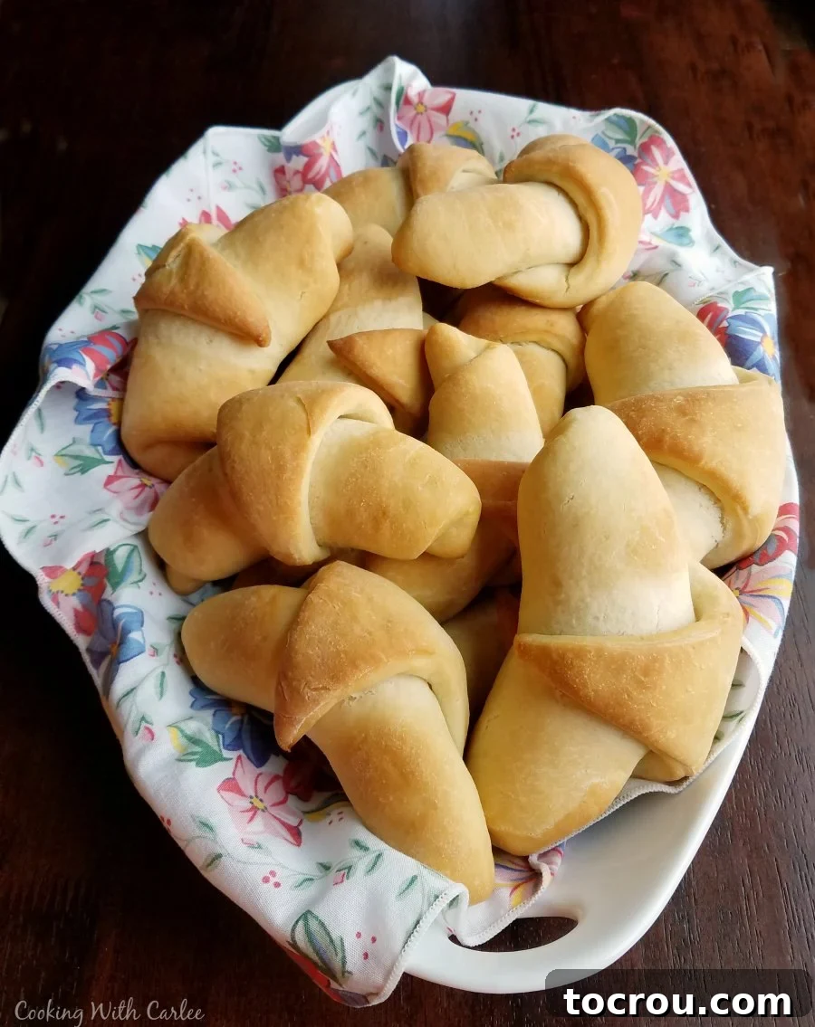 A beautiful serving dish abundantly filled with golden brown sourdough crescent rolls, perfectly arranged and ready to be enjoyed.