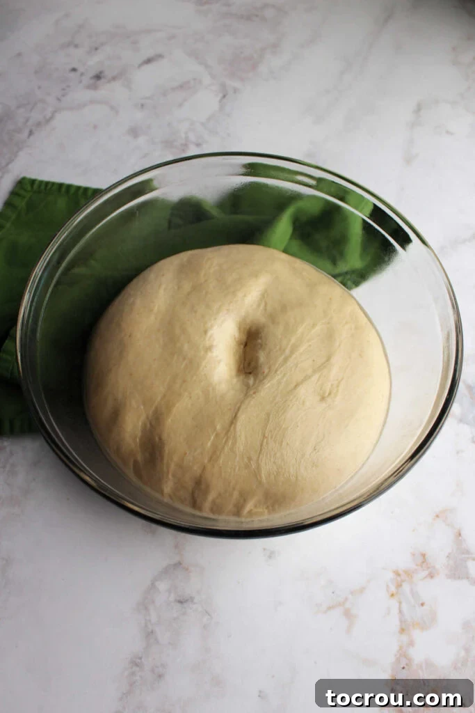 A bowl of perfectly proved sourdough crescent dough, clearly showing a finger indent in the middle, signifying it's ready for shaping.