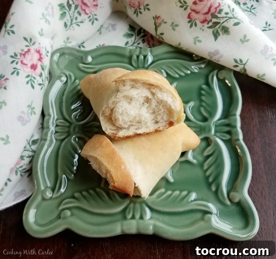 A golden sourdough crescent roll delicately split in half, revealing its incredibly soft, airy, and moist interior.