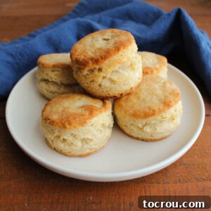 Plate of fluffy, buttery biscuits with golden brown tops and lots of layers.