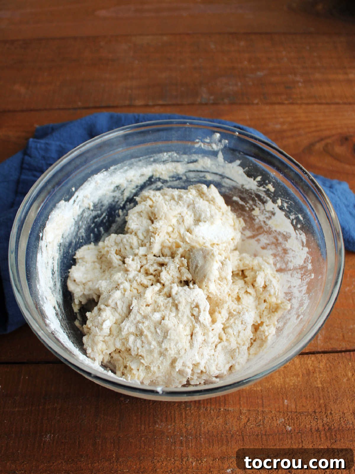Mixing bowl with shaggy biscuit dough inside. A close-up showing the ideal sticky consistency.