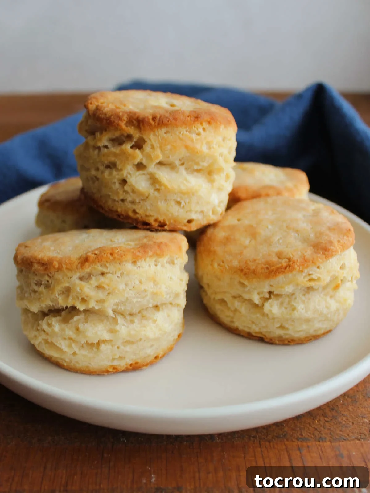 Plate of freshly baked buttery biscuits showing flaky texture on the sides and golden brown tops. An inviting presentation.