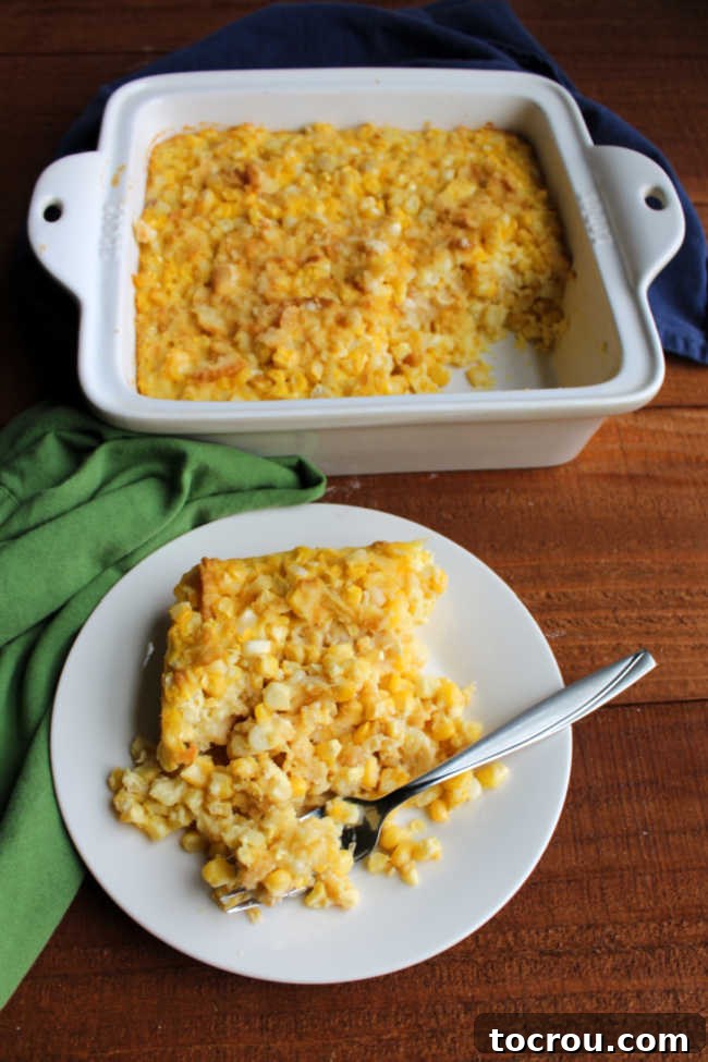 Ready to enjoy: Scalloped Corn Casserole on a plate with a fork. A close-up of a plate with a generous serving of scalloped corn casserole, a fork poised to take a bite, highlighting its tempting texture.