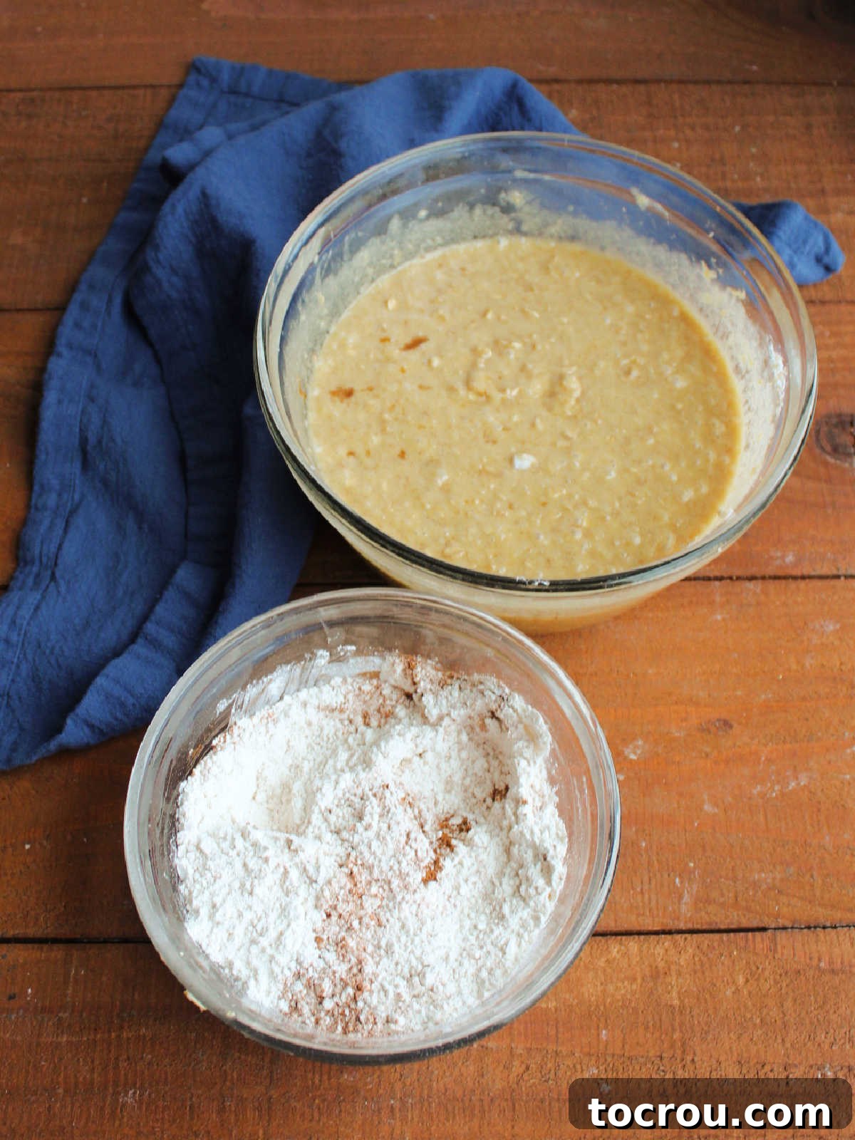 Bowl of wet ingredients mixture next to mixing bowl with flour, baking soda, cinnamon, and salt. 