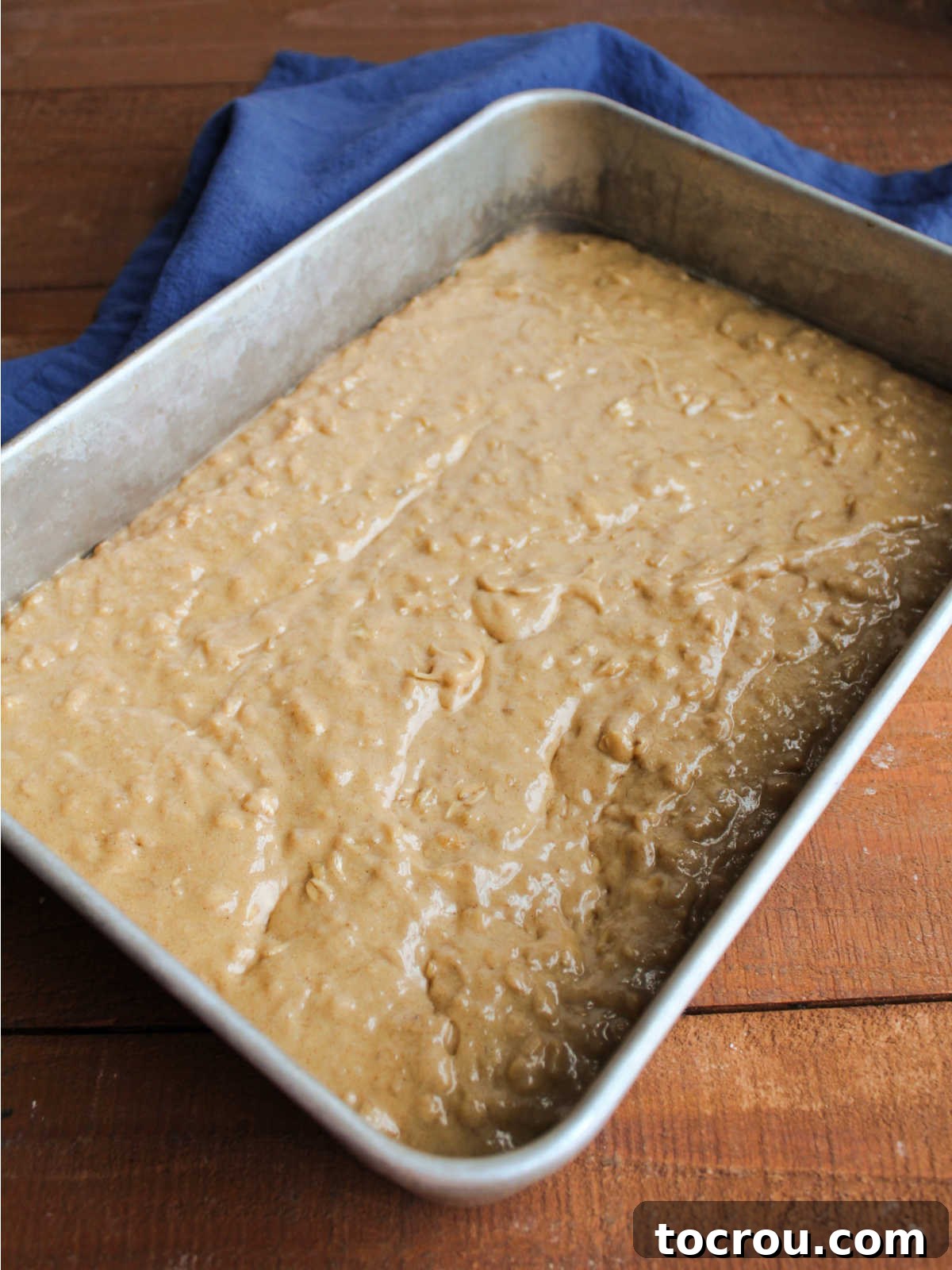 Tan oatmeal cake batter in pan, ready to go in the oven. 